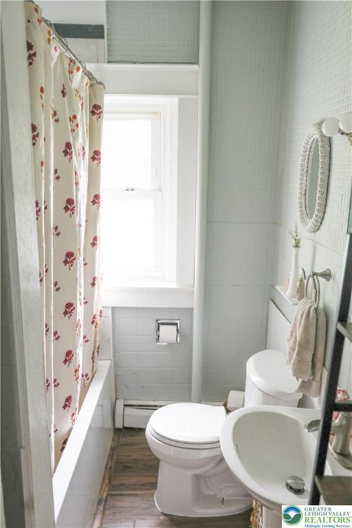 5242 3rd St, Whitehall Twp, PA 18052 - bathroom with tile walls, wood finished floors, a baseboard heating unit, and shower / tub combo with curtain