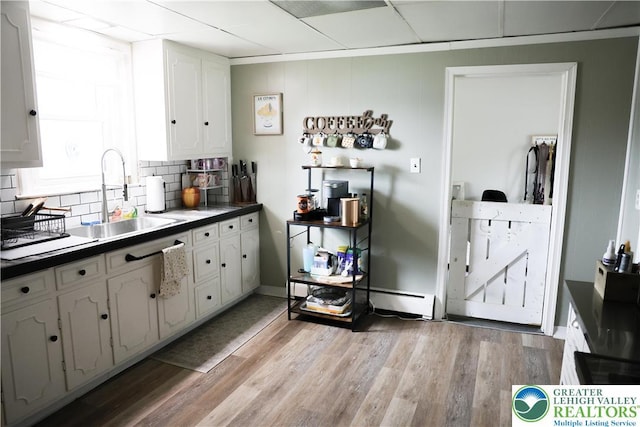 5242 3rd St, Whitehall Twp, PA 18052 - kitchen featuring baseboard heating, white cabinetry, backsplash, light wood-style floors, and dark countertops