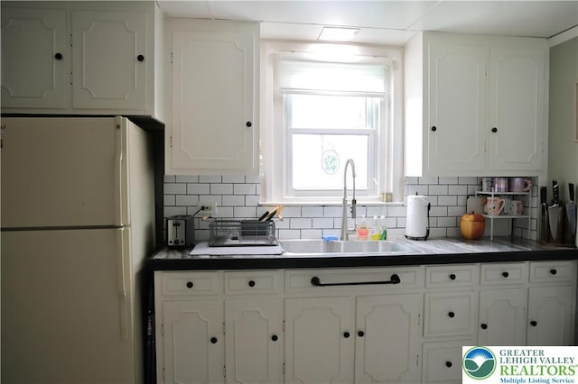 5242 3rd St, Whitehall Twp, PA 18052 - kitchen with freestanding refrigerator, white cabinetry, dark countertops, and decorative backsplash