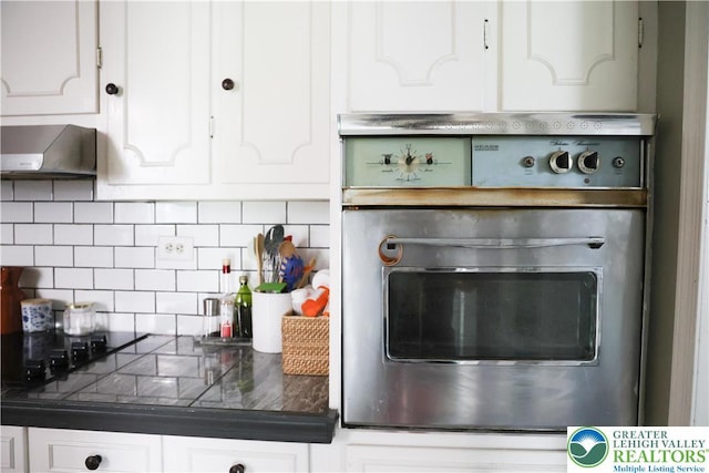 5242 3rd St, Whitehall Twp, PA 18052 - kitchen with oven, wall chimney range hood, white cabinetry, tasteful backsplash, and dark countertops