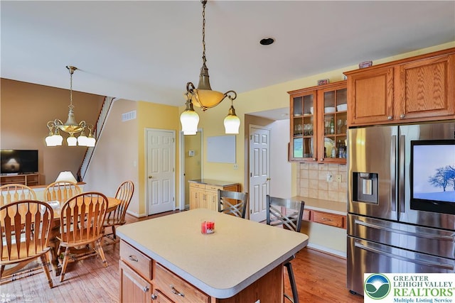 10 Windrift Ct, Easton, PA 18045 - kitchen featuring stainless steel refrigerator with ice dispenser, light wood-style floors, brown cabinetry, tasteful backsplash, and glass insert cabinets