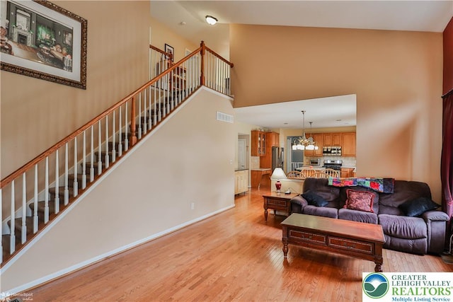 10 Windrift Ct, Easton, PA 18045 - living room featuring light wood finished floors, a towering ceiling, stairway, and a chandelier