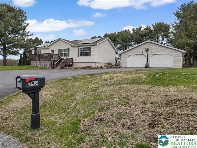 3954 Cedar Dr, Lehigh Twp, PA 18088 - view of front of home with a detached garage, a wooden deck, a front yard, an outbuilding, and roof mounted solar panels