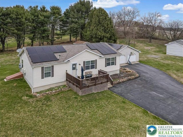 3954 Cedar Dr, Lehigh Twp, PA 18088 - back of property with roof with shingles, a deck, a lawn, roof mounted solar panels, and an outbuilding