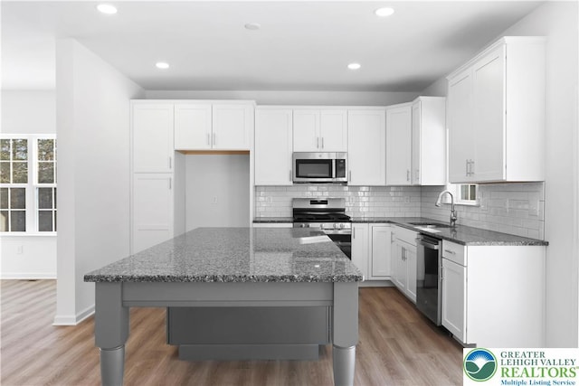 718 Rte 314 Unit 2, Pocono Twp, PA 18370 - kitchen with appliances with stainless steel finishes, dark stone countertops, light wood-style flooring, white cabinetry, and backsplash