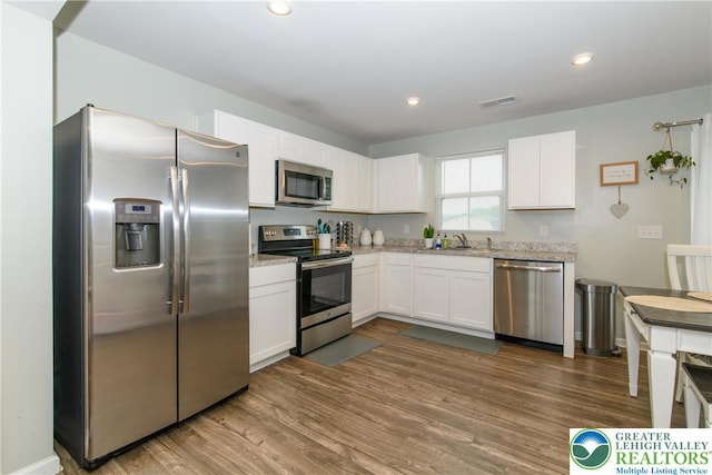 403 Lock Dr, Allen Twp, PA 18067 - kitchen featuring appliances with stainless steel finishes, white cabinets, dark wood finished floors, light stone counters, and recessed lighting