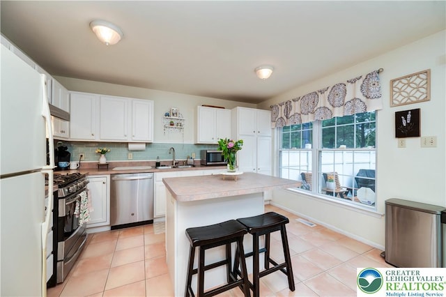1778 Pinewind Dr, Alburtis Boro, PA 18011 - kitchen with appliances with stainless steel finishes, white cabinetry, light countertops, a breakfast bar, and decorative backsplash