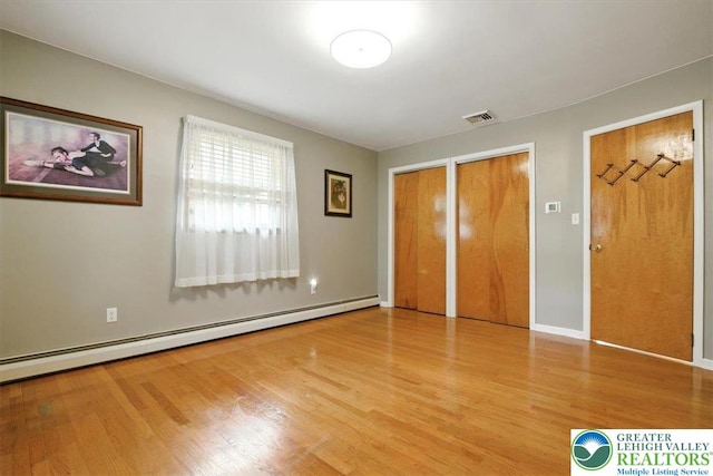 627 Columbia Ave, Palmerton Boro, PA 18071 - unfurnished bedroom featuring multiple closets, a baseboard heating unit, and wood finished floors