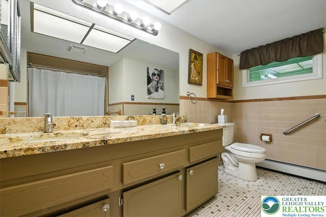 627 Columbia Ave, Palmerton Boro, PA 18071 - bathroom featuring double vanity, tile walls, wainscoting, baseboard heating, and tile patterned flooring