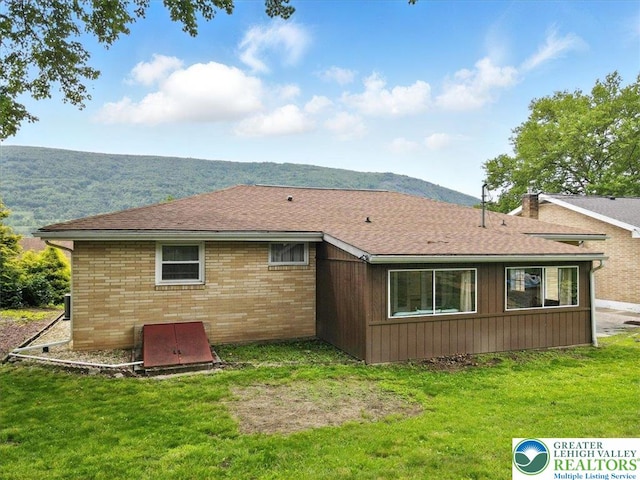 627 Columbia Ave, Palmerton Boro, PA 18071 - back of house featuring a yard, a mountain view, brick siding, a shingled roof, and a chimney