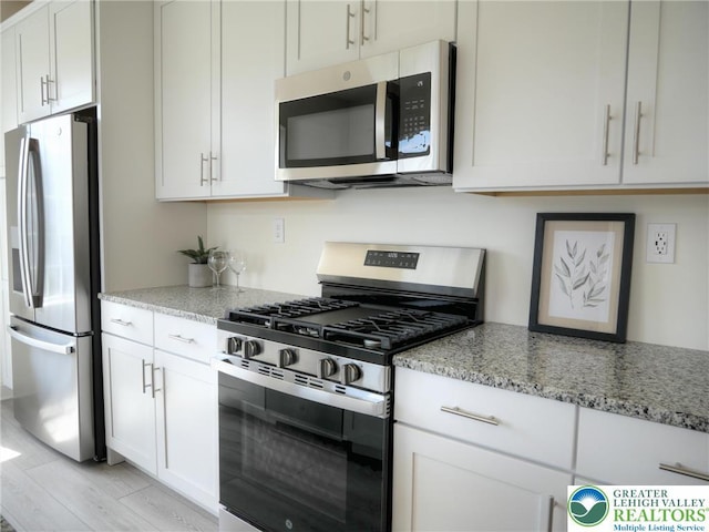 868 Veneto Ct, Forks Twp, PA 18040 - kitchen with stainless steel appliances, light stone countertops, light wood-style flooring, and white cabinetry