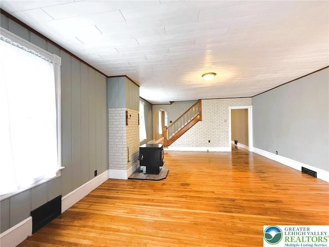 233 Lafayette Ave, Palmerton Boro, PA 18071 - unfurnished living room featuring a wood stove, light wood finished floors, arched walkways, brick wall, and ornamental molding