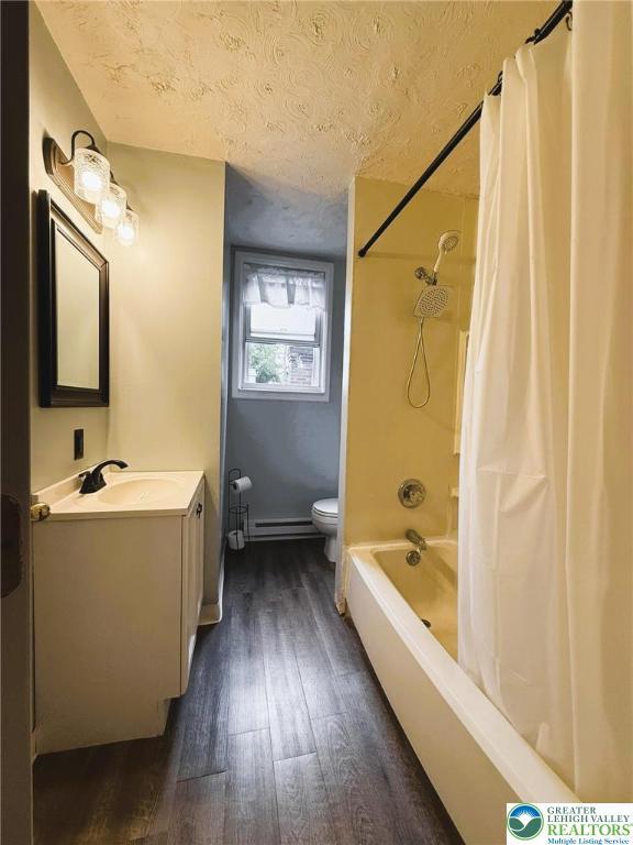 233 Lafayette Ave, Palmerton Boro, PA 18071 - bathroom featuring wood finished floors, a textured ceiling, vanity, shower / bath combo with shower curtain, and a baseboard radiator