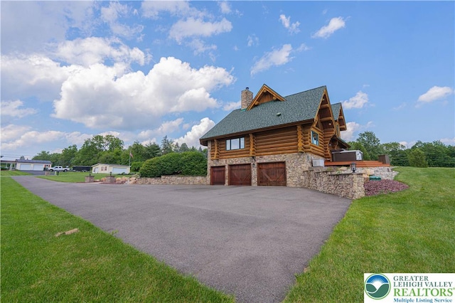 379 Meyer Rd, Bushkill Twp, PA 18064 - view of side of property with log exterior, a chimney, an attached garage, a lawn, and stone siding