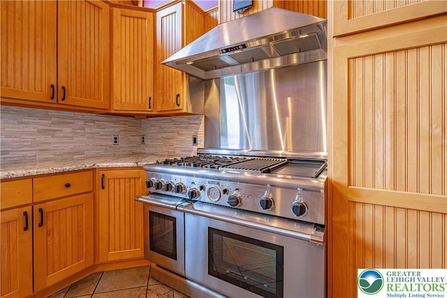 379 Meyer Rd, Bushkill Twp, PA 18064 - kitchen with range with two ovens, exhaust hood, decorative backsplash, light tile patterned floors, and light stone countertops