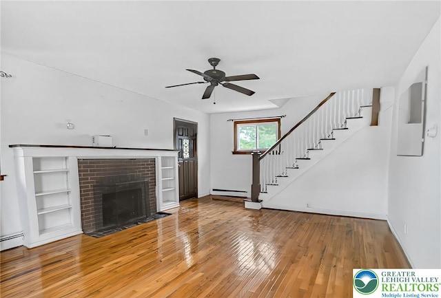 815 Summit Ave, Prospect Park, PA 19076 - unfurnished living room featuring stairs, baseboard heating, ceiling fan, hardwood / wood-style flooring, and a brick fireplace