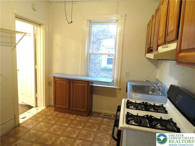 2206 Forest St, Wilson Boro, PA 18042 - kitchen featuring under cabinet range hood, white gas range, brown cabinets, light countertops, and light floors