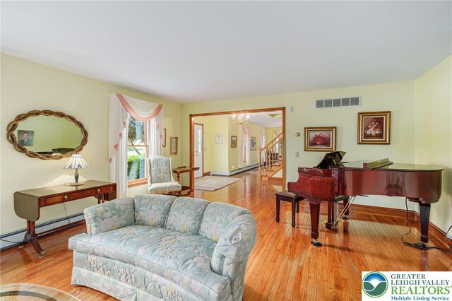 1151 Marfield Dr, Bushkill Twp, PA 18064 - living area featuring wood finished floors, baseboard heating, a chandelier, and stairway