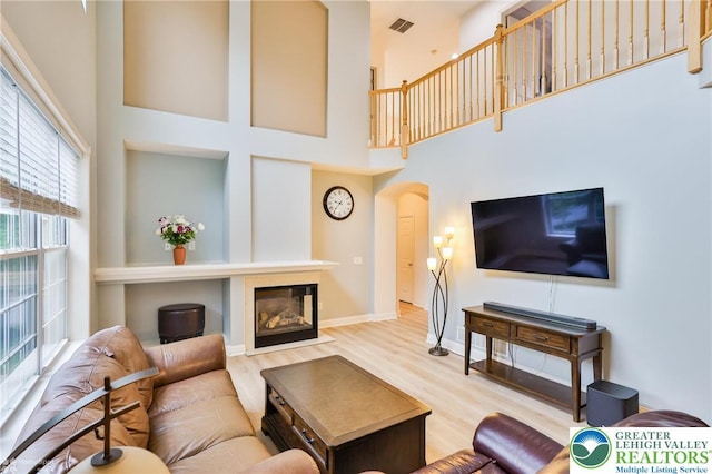 780 Ramblewood Dr, Forks Twp, PA 18040 - living area featuring wood finished floors, a towering ceiling, a glass covered fireplace, and arched walkways