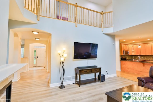 780 Ramblewood Dr, Forks Twp, PA 18040 - living area featuring light wood-type flooring, a towering ceiling, and arched walkways