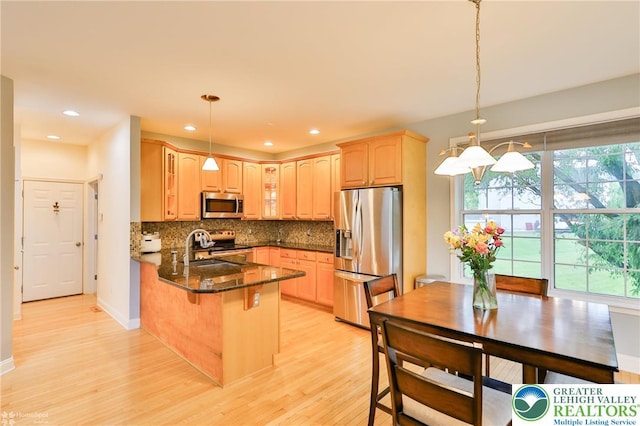 780 Ramblewood Dr, Forks Twp, PA 18040 - kitchen featuring appliances with stainless steel finishes, a peninsula, glass insert cabinets, light wood-style floors, and decorative backsplash