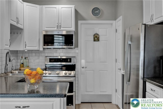 4693 Bluegrass Ln, Lower Macungie Twp, PA 18062 - kitchen featuring stainless steel appliances, dark countertops, white cabinetry, decorative backsplash, and light tile patterned flooring