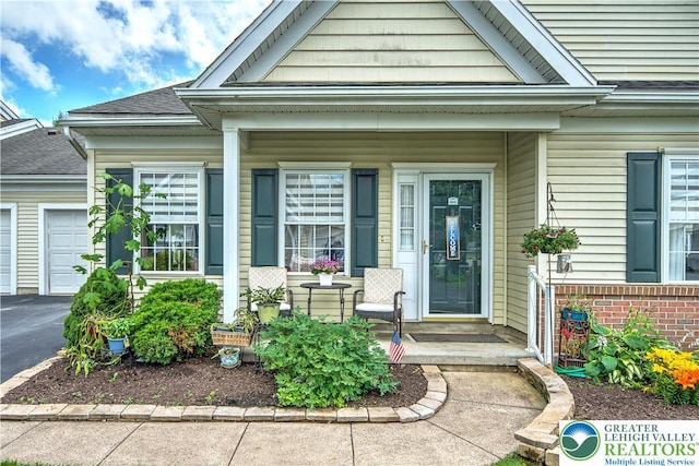 4693 Bluegrass Ln, Lower Macungie Twp, PA 18062 - view of exterior entry featuring covered porch, roof with shingles, driveway, and a garage