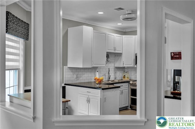 4693 Bluegrass Ln, Lower Macungie Twp, PA 18062 - kitchen with white cabinets, decorative backsplash, crown molding, dark countertops, and recessed lighting