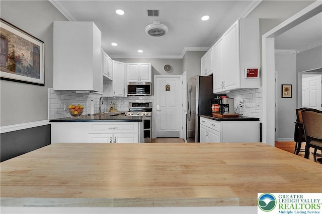 4693 Bluegrass Ln, Lower Macungie Twp, PA 18062 - kitchen featuring appliances with stainless steel finishes, decorative backsplash, white cabinetry, crown molding, and recessed lighting