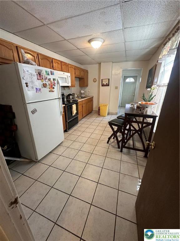 172 Tilghman St, Allentown City, PA 18102 - kitchen with white appliances, a paneled ceiling, light tile patterned floors, brown cabinetry, and light countertops