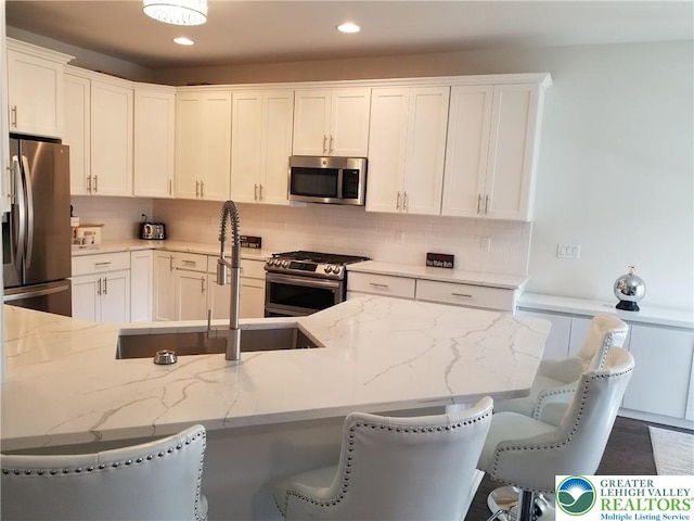 3583 Daylily Dr, Upper Milford Twp, PA 18049 - kitchen with stainless steel appliances, a kitchen bar, white cabinets, light stone countertops, and tasteful backsplash