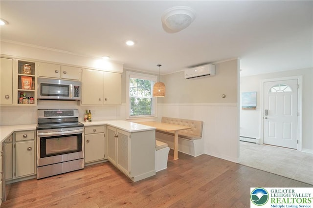 11 11 Ave, D, PA 17972 - kitchen featuring stainless steel appliances, a wall mounted AC, baseboard heating, light countertops, and cream cabinetry