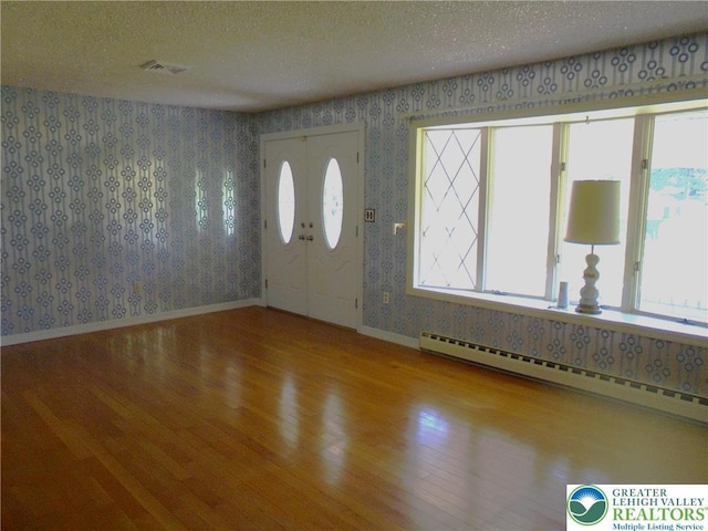 2546 Wehr Mill Rd, South Whitehall Twp, PA 18069 - foyer with wood-type flooring, healthy amount of natural light, a baseboard heating unit, wallpapered walls, and a textured ceiling