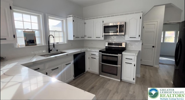 106 Lynx Ln, Chestnuthill Twp, PA 18330 - kitchen with stainless steel appliances, light wood-style flooring, light stone counters, and white cabinetry
