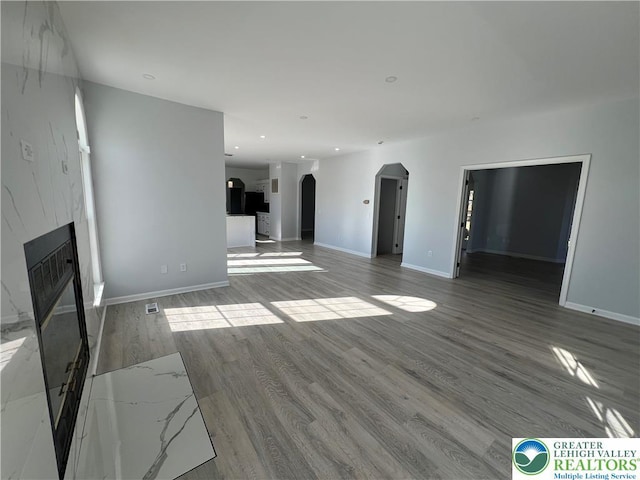 106 Lynx Ln, Chestnuthill Twp, PA 18330 - unfurnished living room with arched walkways, a fireplace, wood finished floors, and recessed lighting