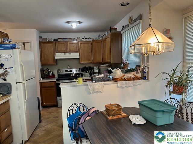 255 Ridings Cir, Macungie Boro, PA 18062 - kitchen with electric range, under cabinet range hood, freestanding refrigerator, brown cabinetry, and pendant lighting
