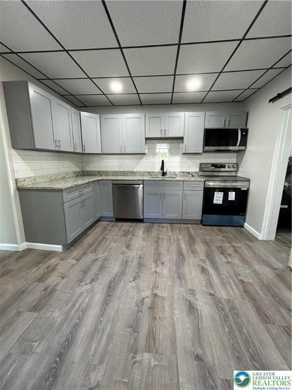 230 White St, Lehighton Boro, PA 18235 - kitchen featuring appliances with stainless steel finishes, light wood-style floors, gray cabinetry, a drop ceiling, and tasteful backsplash