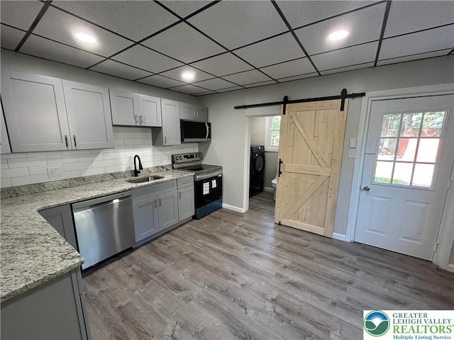 230 White St, Lehighton Boro, PA 18235 - kitchen with appliances with stainless steel finishes, a barn door, tasteful backsplash, wood finished floors, and light stone counters