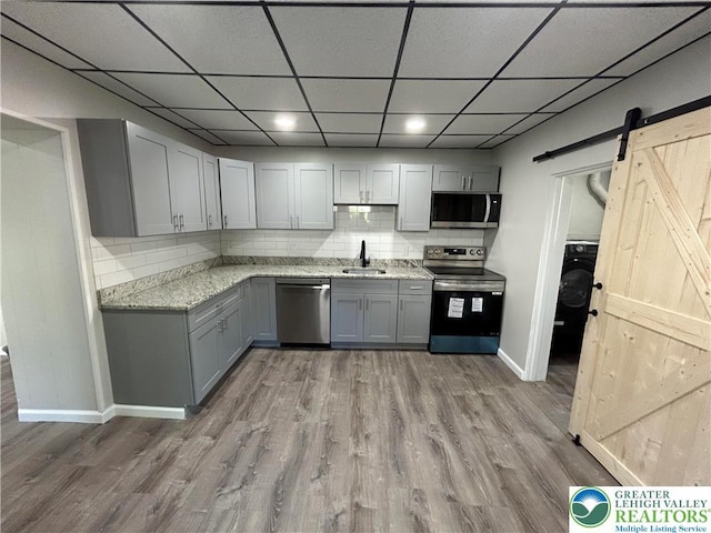 230 White St, Lehighton Boro, PA 18235 - kitchen with stainless steel appliances, gray cabinetry, a barn door, wood finished floors, and washer / dryer