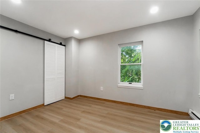 226 Fern St, Jim Thorpe Boro, PA 18229 - unfurnished bedroom with a barn door, a baseboard radiator, light wood-style floors, recessed lighting, and a closet