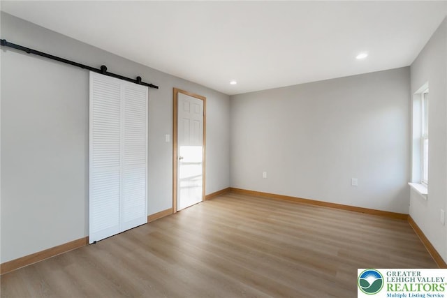 226 Fern St, Jim Thorpe Boro, PA 18229 - unfurnished bedroom featuring a barn door, light wood-style floors, and recessed lighting