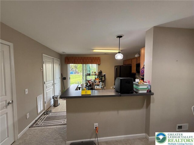 1499 Artisan Ct, Upper Macungie Twp, PA 18031 - kitchen with a peninsula, freestanding refrigerator, dark countertops, brown cabinets, and light colored carpet