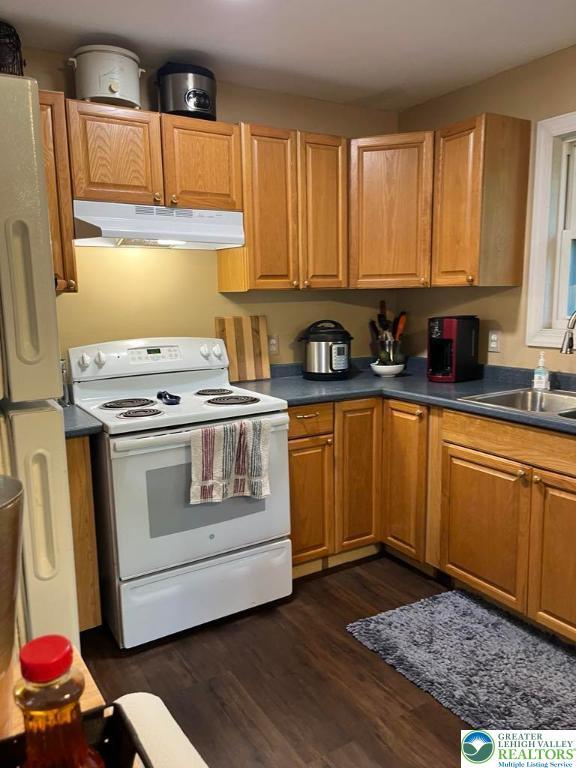 1007 Calypso, Wayne, PA 18436 - kitchen featuring white appliances, under cabinet range hood, dark wood-style floors, dark countertops, and brown cabinets