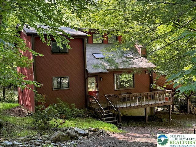 193 Canterbury Rd, Lehman Twp, PA 18324 - view of front of house featuring roof with shingles, a deck, and a chimney
