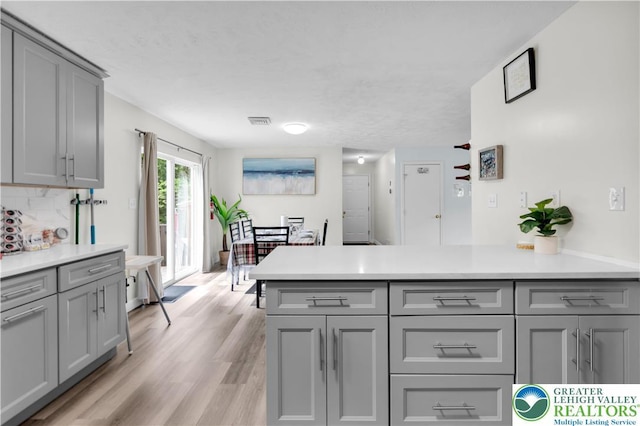 672 Clearview St, Tobyhanna Twp, PA 18334 - kitchen with gray cabinetry, light countertops, light wood-style floors, and decorative backsplash