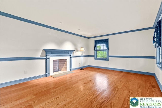 6513 Station Vw, Upper Milford Twp, PA 18092 - unfurnished living room with wood finished floors, a fireplace with raised hearth, and ornamental molding