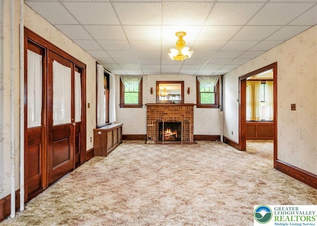 2834 Interchange Rd, Franklin Twp, PA 18235 - unfurnished living room featuring carpet flooring, healthy amount of natural light, a brick fireplace, a paneled ceiling, and wallpapered walls