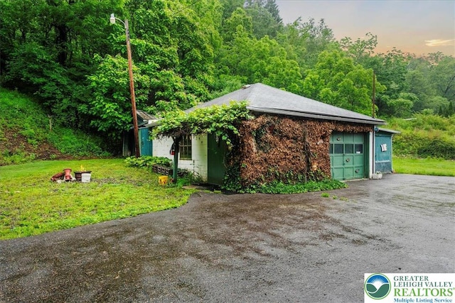 2834 Interchange Rd, Franklin Twp, PA 18235 - view of side of property with driveway, an attached garage, a wooded view, and a lawn