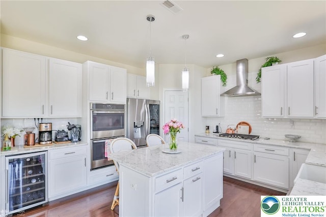 249 Danbury Dr, Upper Nazareth Twp, PA 18064 - kitchen with beverage cooler, appliances with stainless steel finishes, wall chimney exhaust hood, backsplash, and white cabinets