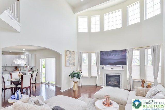 249 Danbury Dr, Upper Nazareth Twp, PA 18064 - living room with a towering ceiling, dark wood-style floors, arched walkways, and a glass covered fireplace